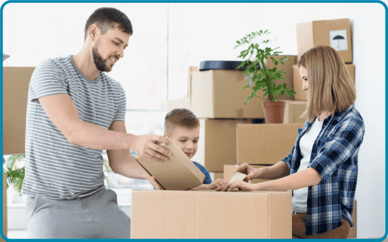 What is the least expensive day to move long distance? A young family enjoying themselves while packing up some boxes for moving day.