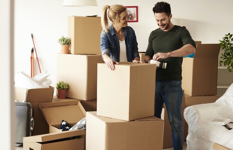 How do I pack my house for a long distance move? A young couple enjoying themselves while packing up the house for moving day.